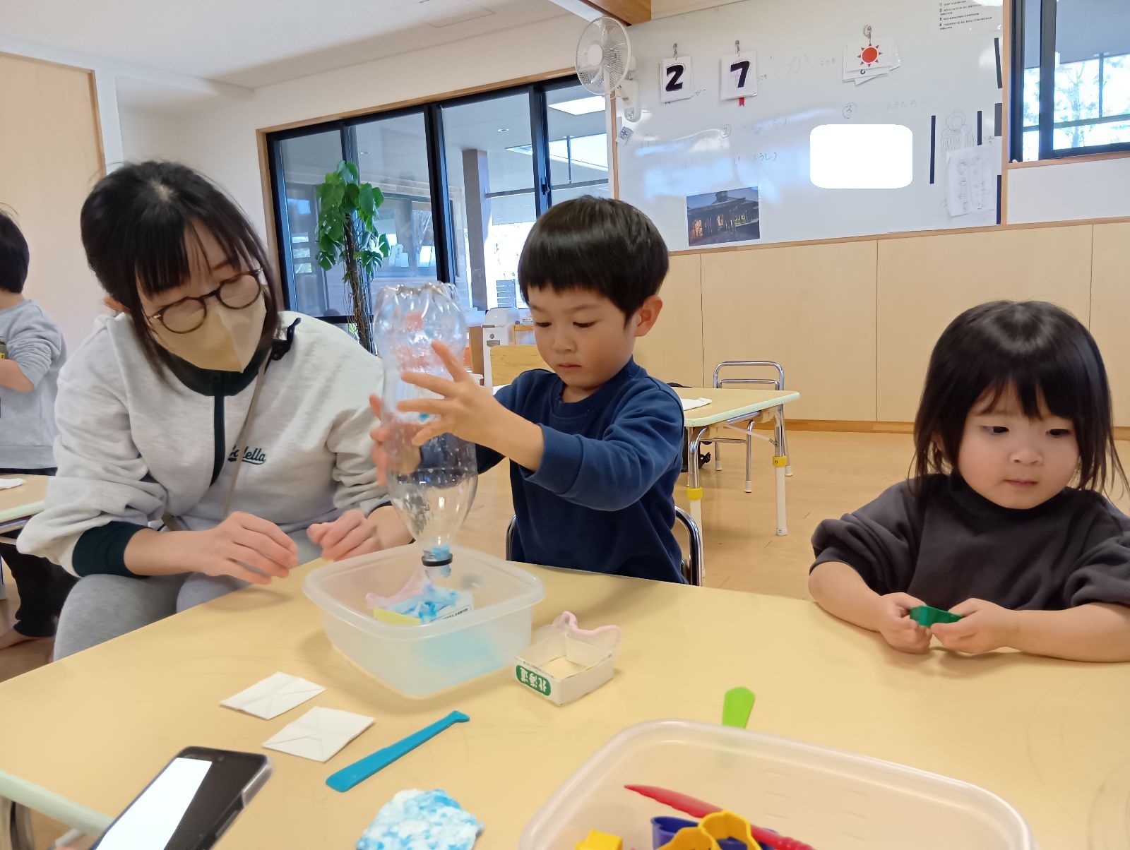 ペットボトルを逆さにして中に入っている紙を取り出す子ども