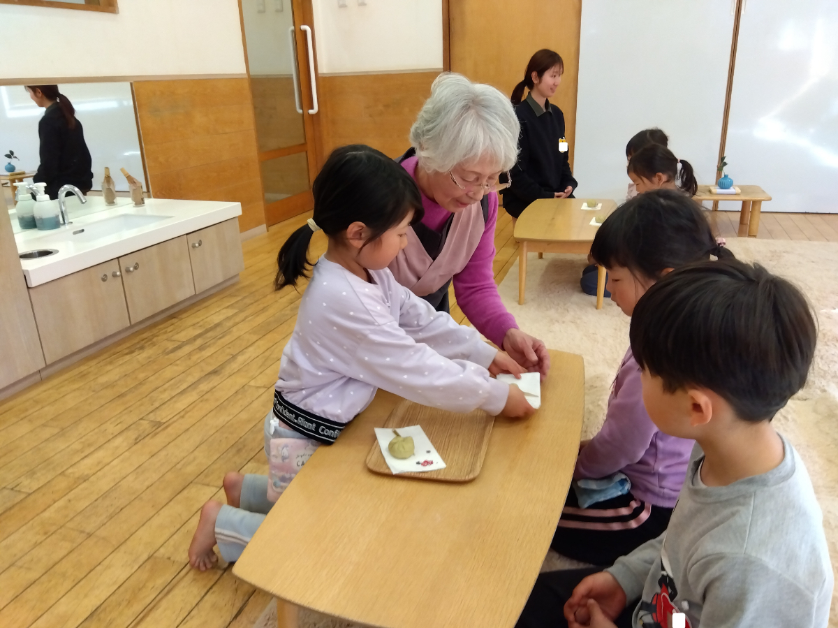 友だちにお茶菓子を渡す子ども