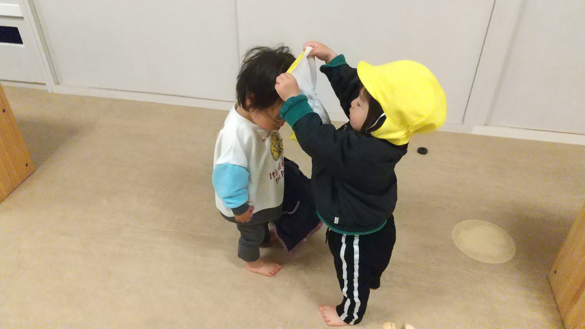 他児に帽子をかぶせようとする姿