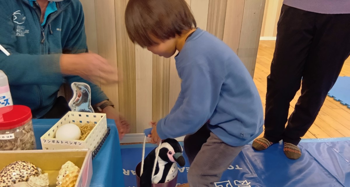 分ボルトペンギンの重さを体験する子ども