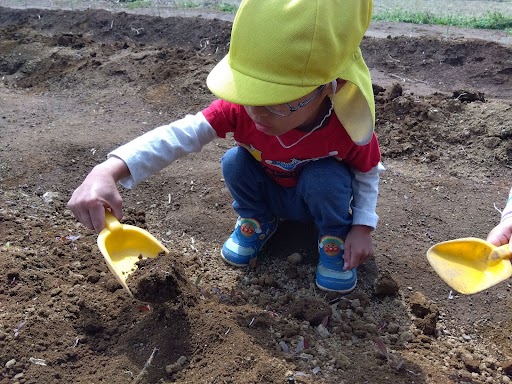 スコップで土を掘る子どもたち