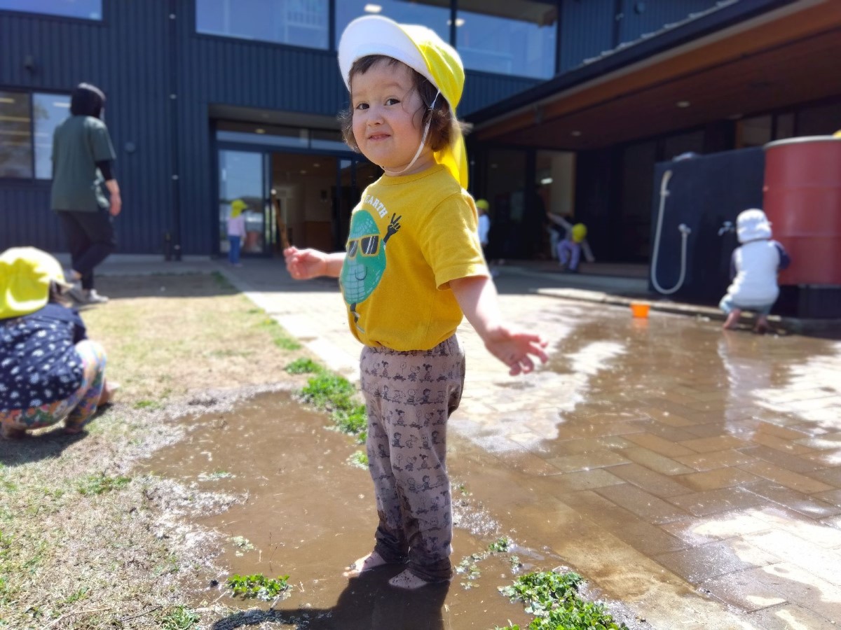 園庭で泥遊びをする子ども