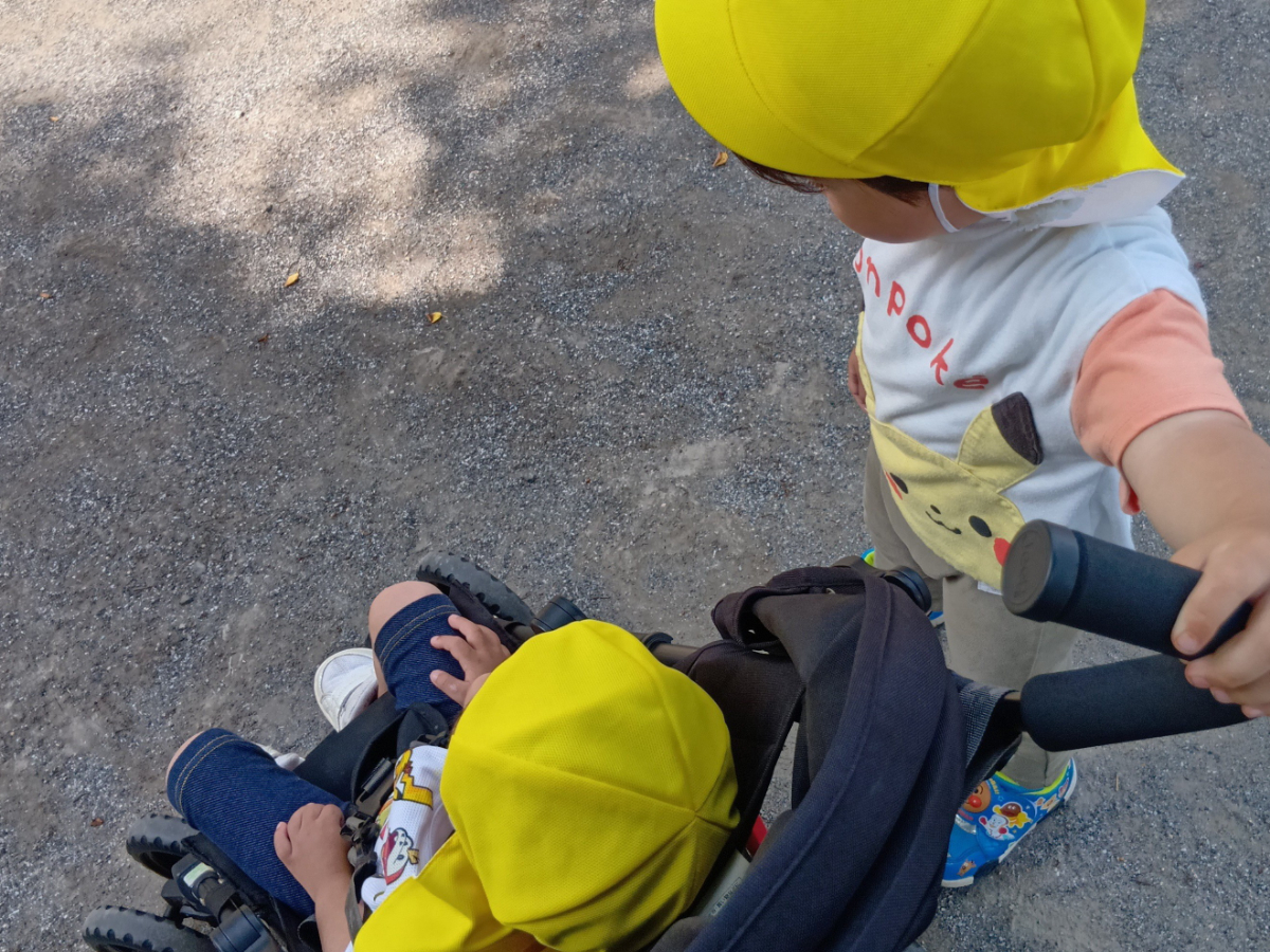友だちが乗るベビーカーを押す子ども