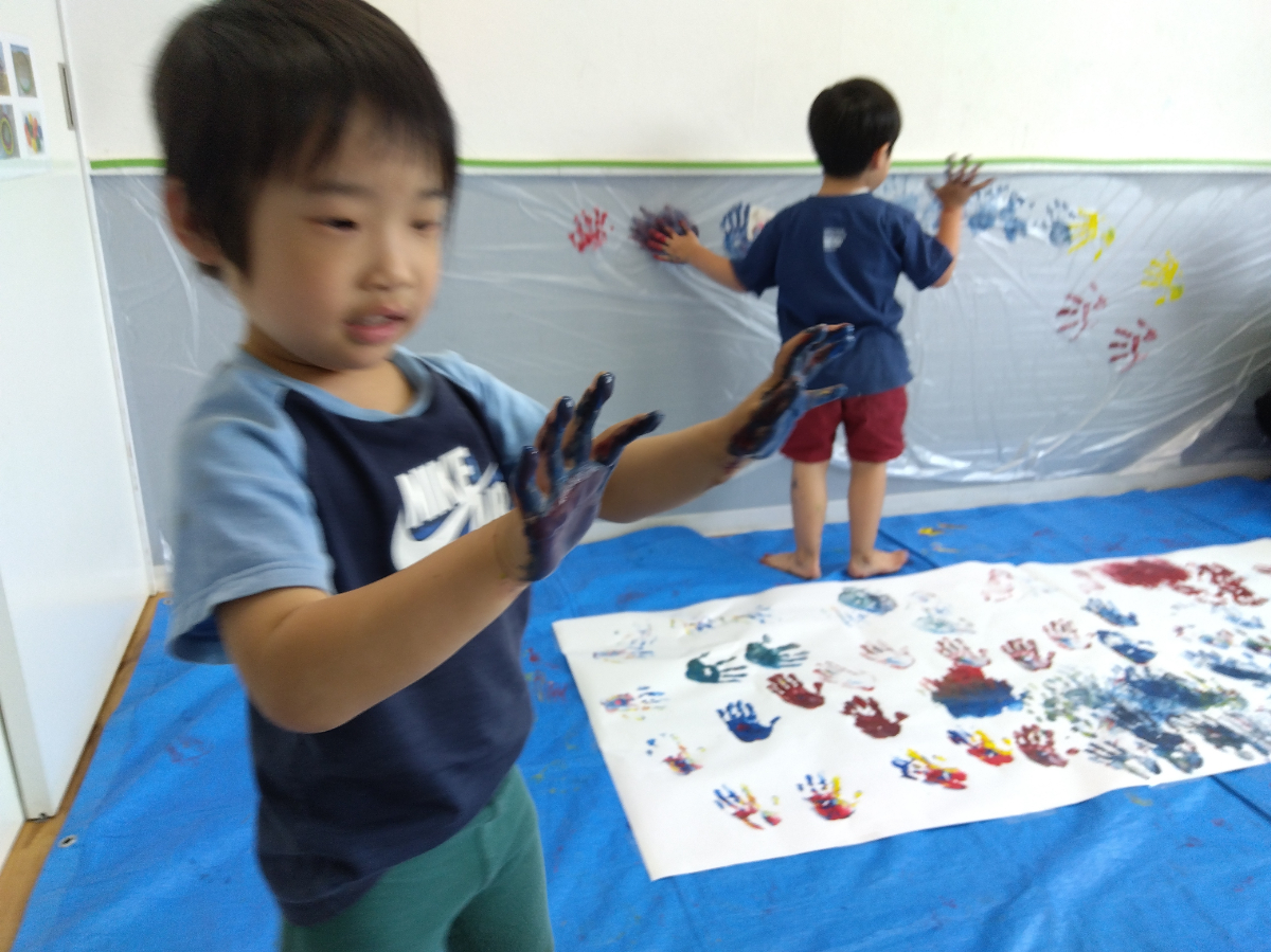 壁や床に絵の具で手形をつける子ども