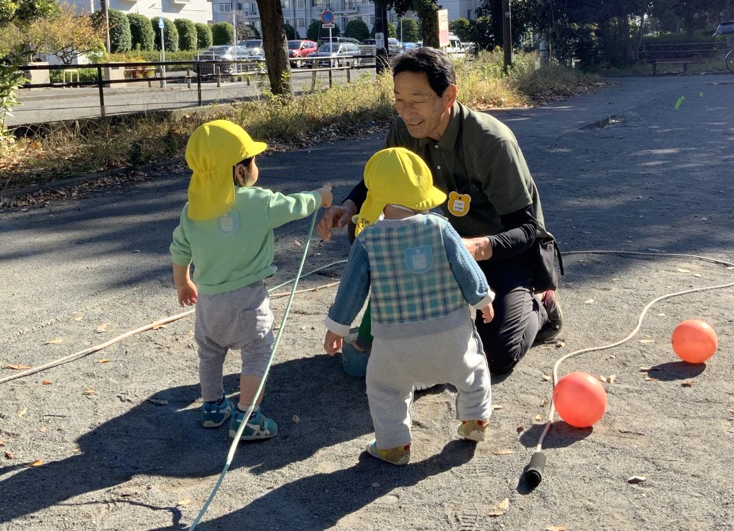 長身をかがめて1歳児と遊ぶ