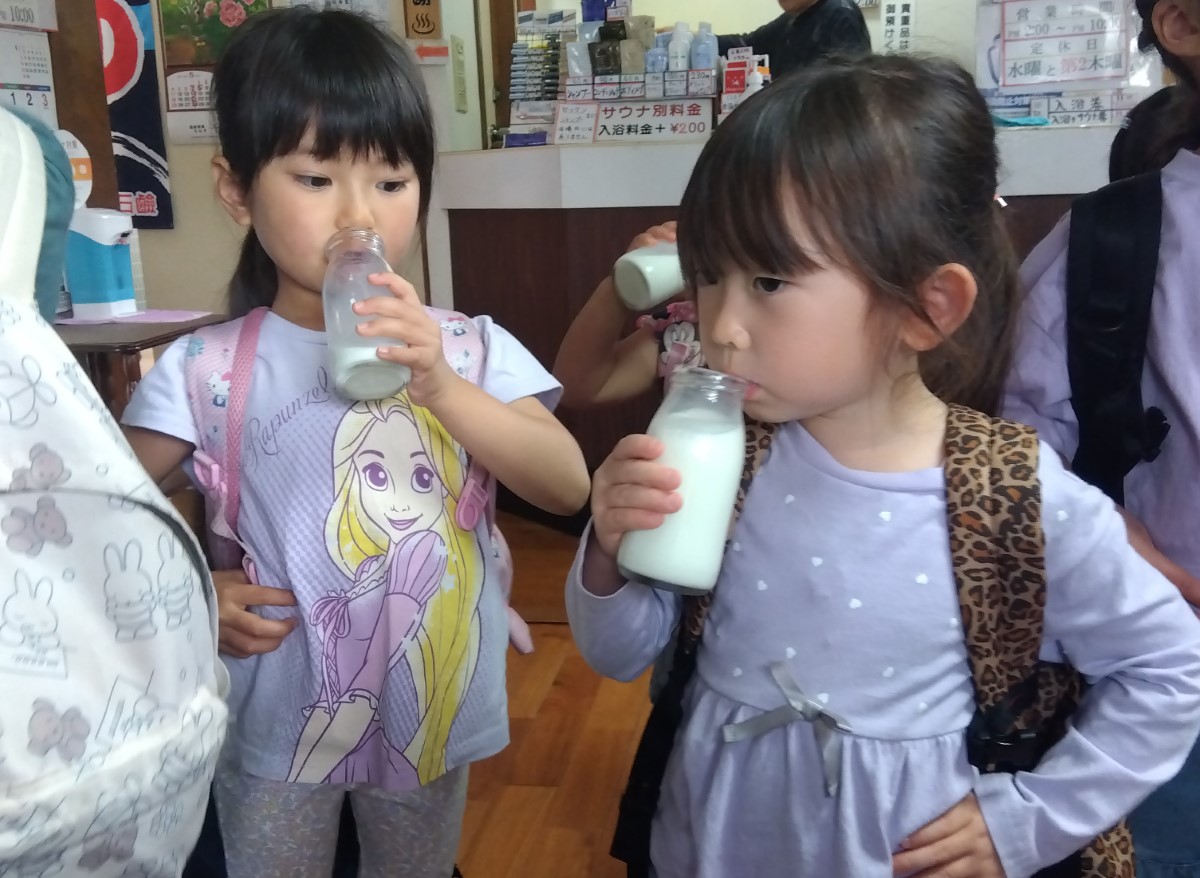 腰に手をあて瓶牛乳を飲む子どもたち