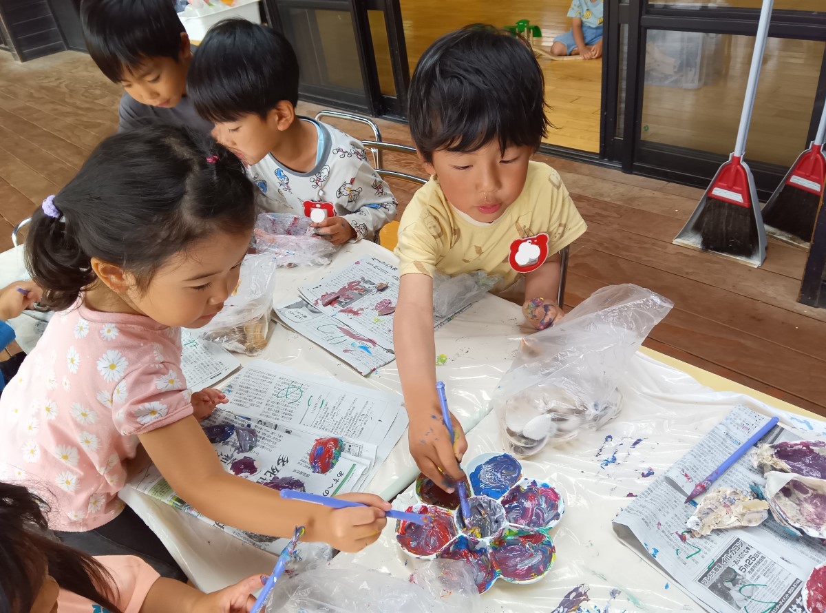 貝殻に絵の具で色を塗る子どもたち