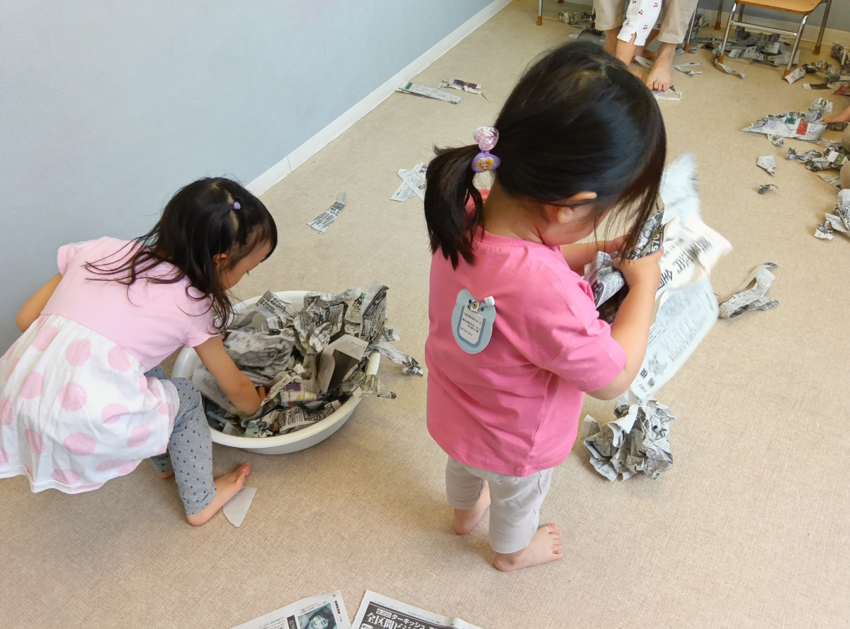 新聞紙遊びをする子どもたち