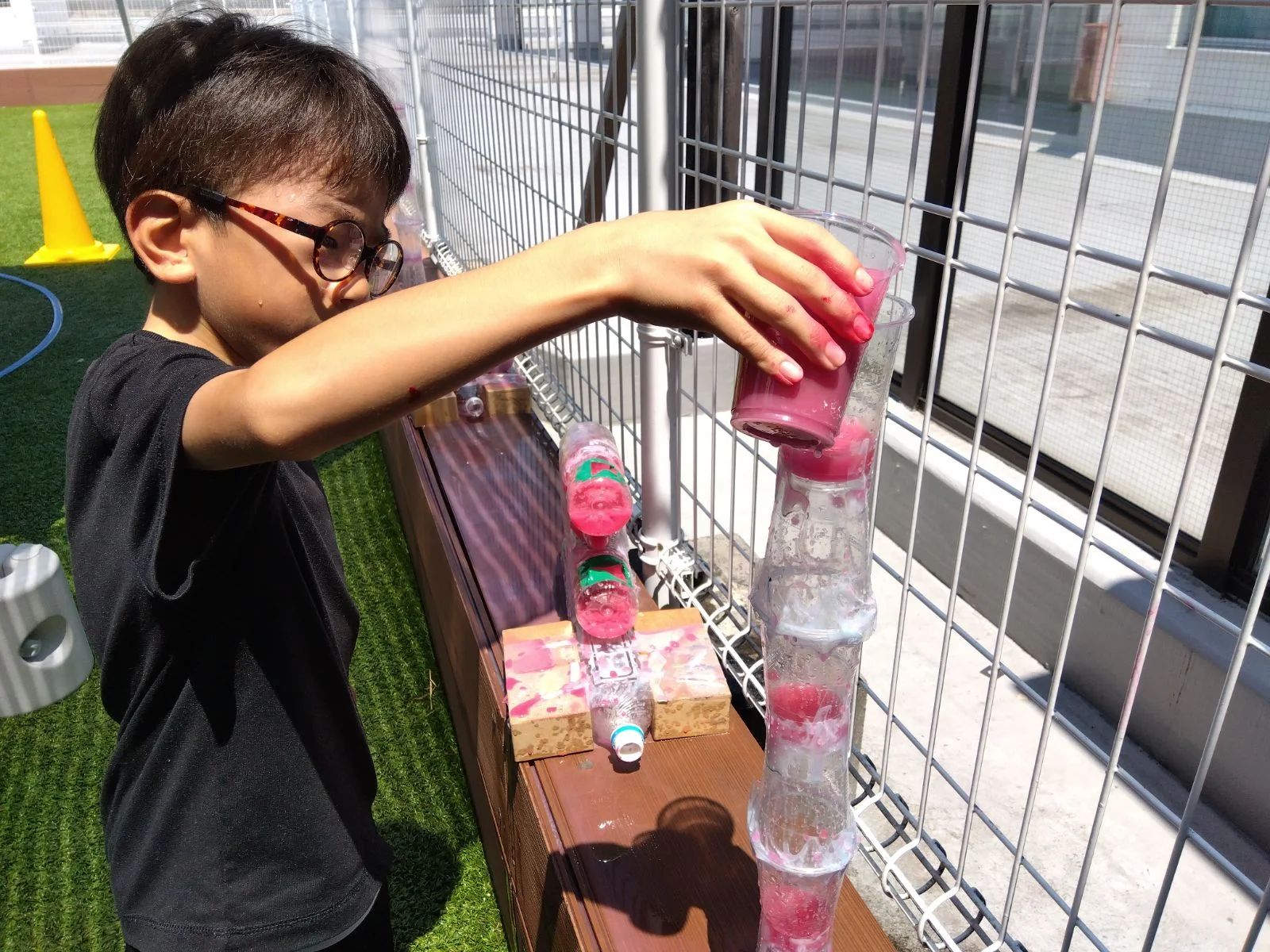 ペットボトルタワーに水を流す子ども