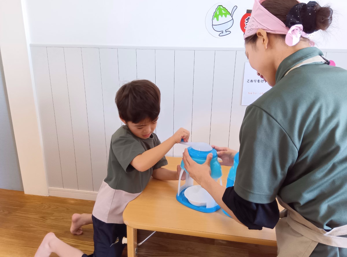 かき氷機で氷を削る子ども