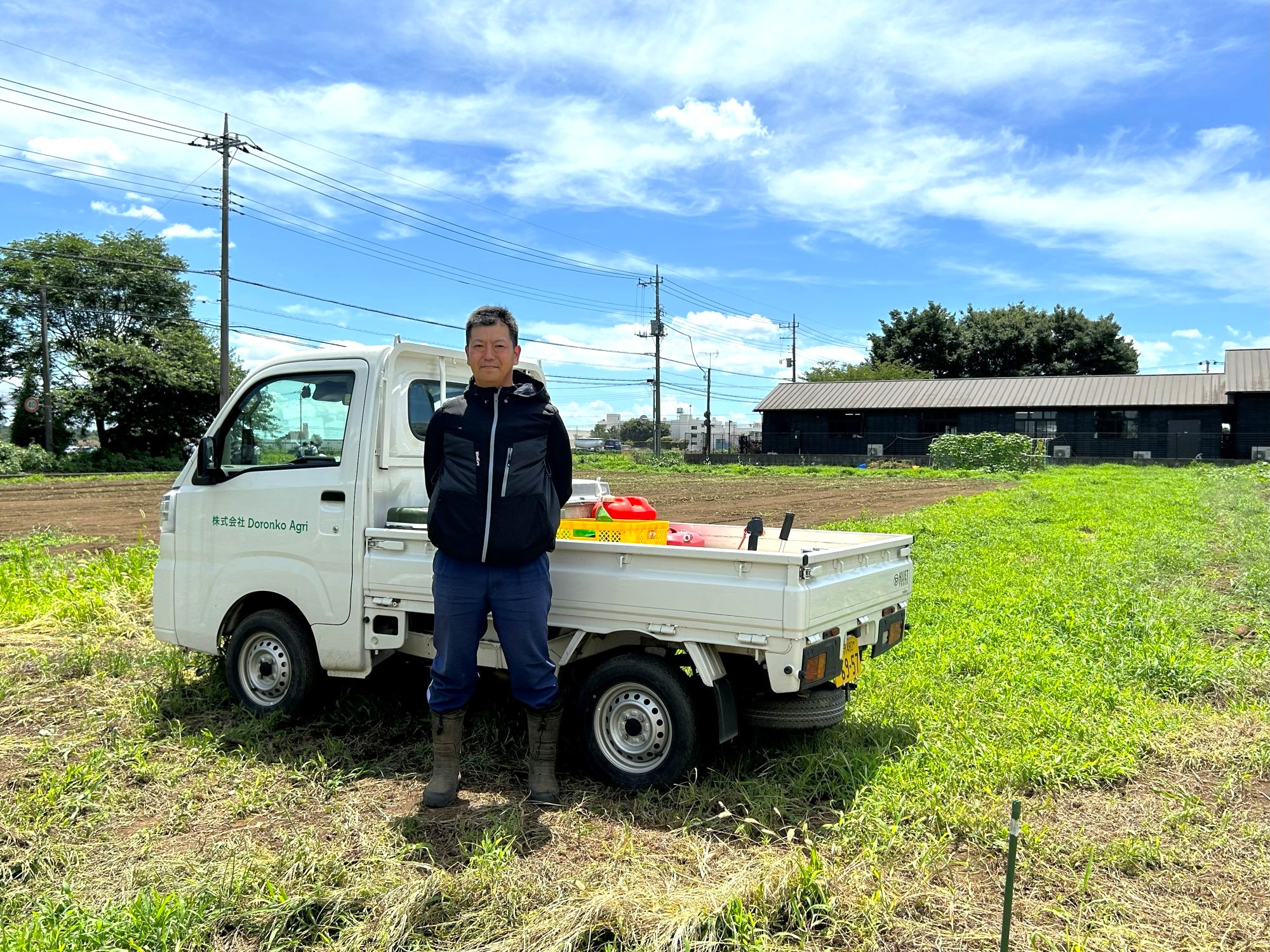 畑の前でこちらを向く新井さん