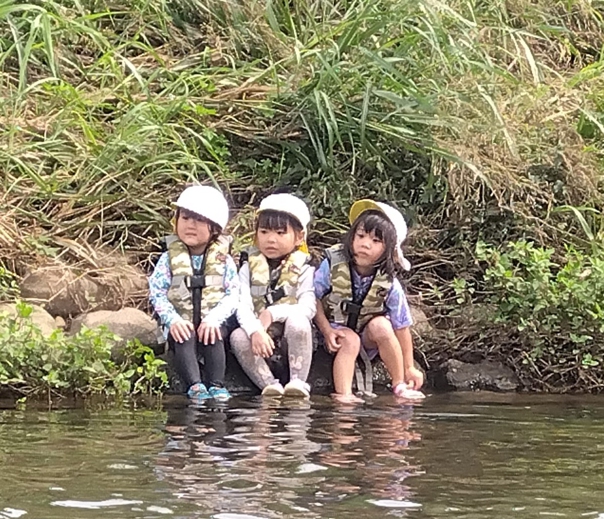 川の土手に座る子どもたち