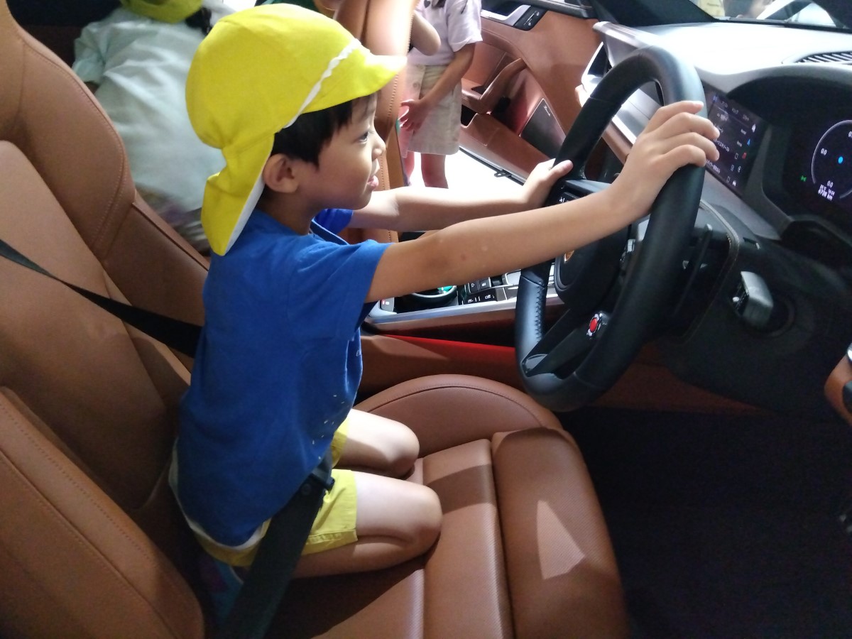 車の運転席に載せてもらう子ども
