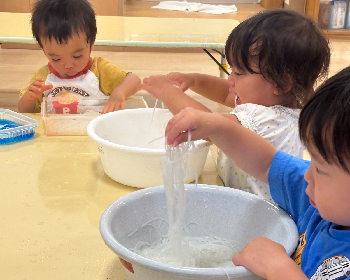 春雨に触れて遊ぶ子どもたち