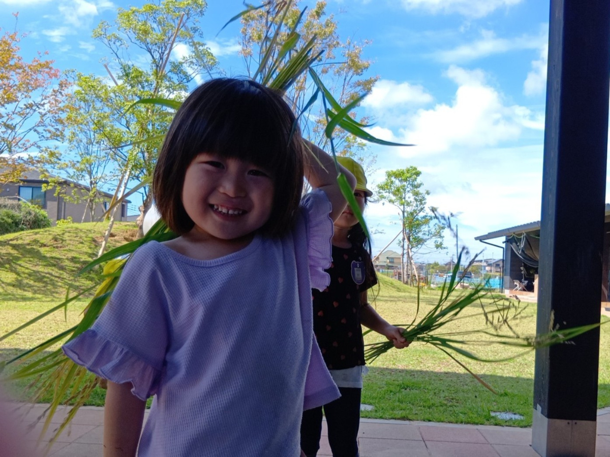 稲穂をもって笑顔の子ども