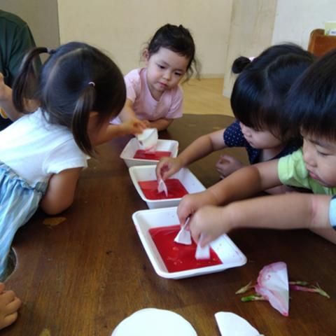 赤い染め液に和紙を浸す子どもたち