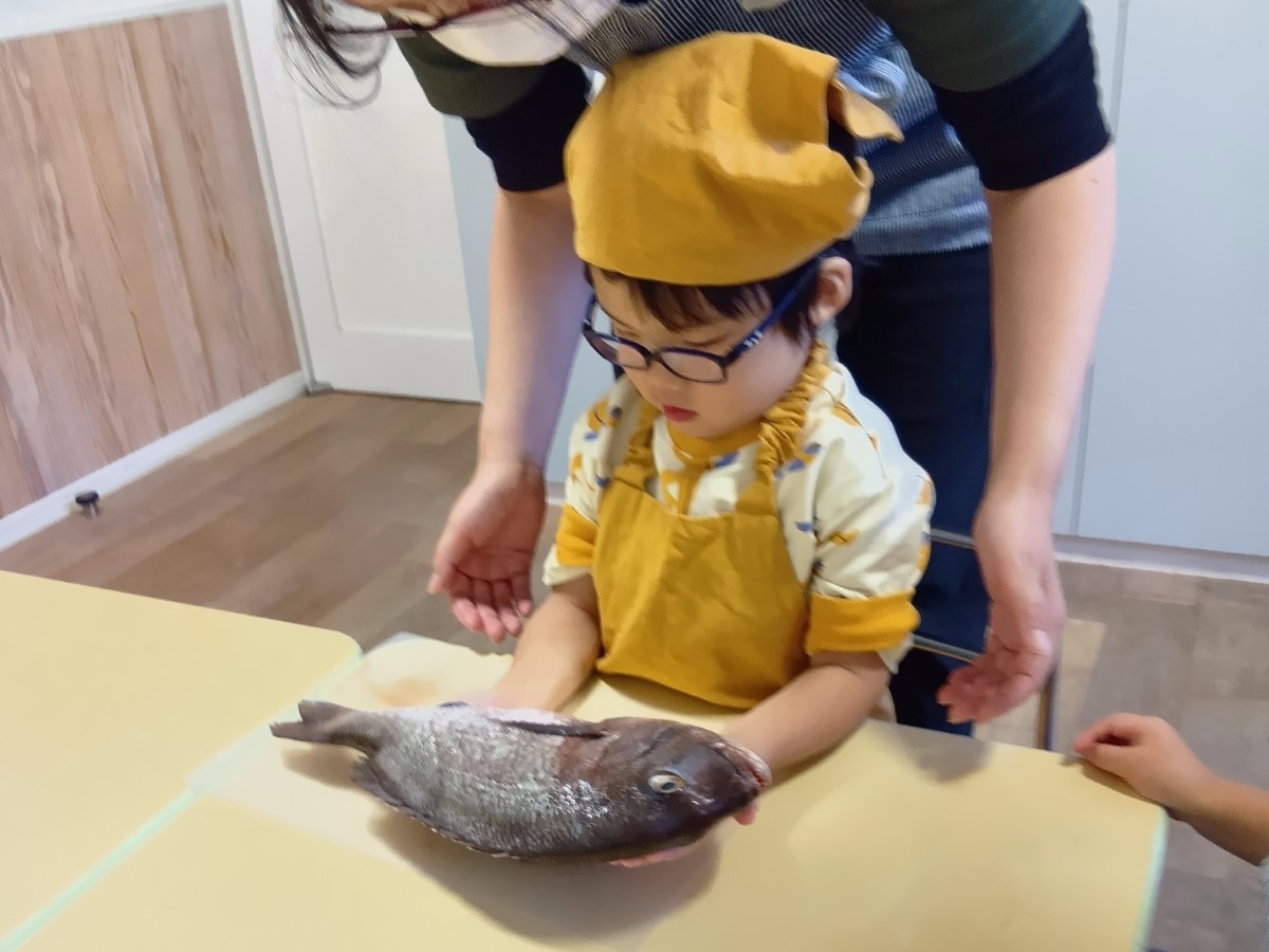 鯛を丸ごと一匹手に載せる子ども