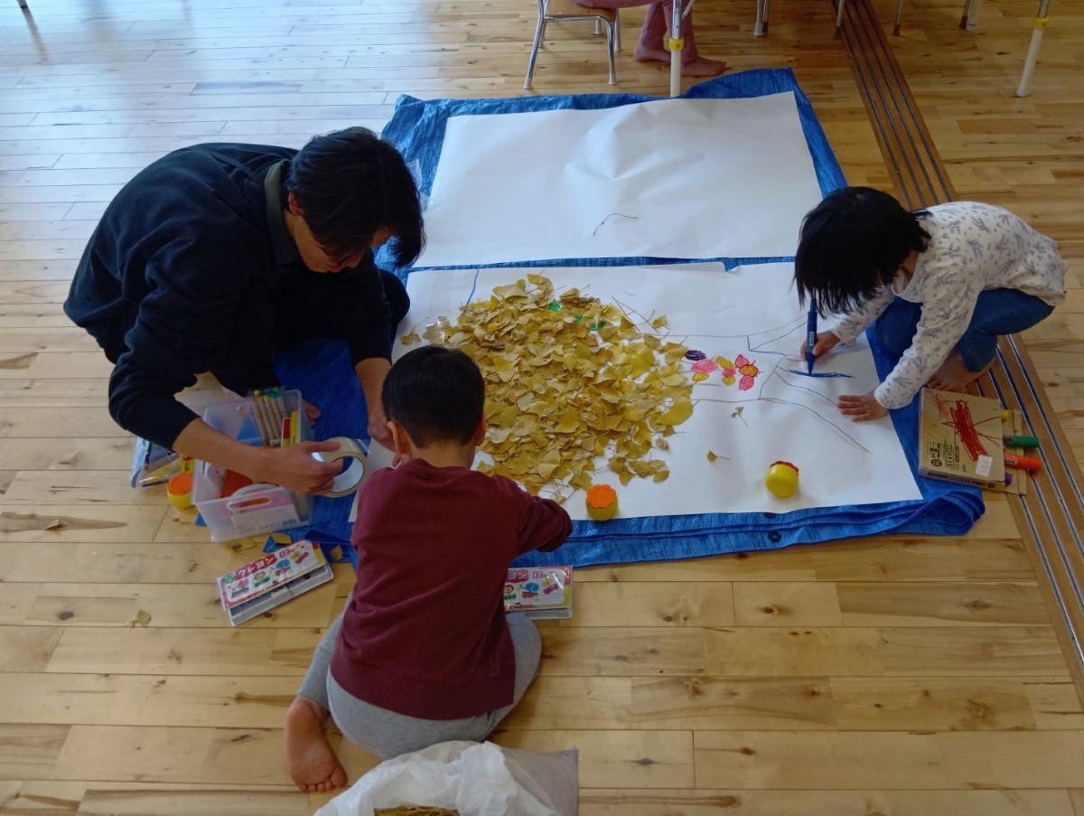 大きな紙にイチョウの葉を貼り付ける子どもたち