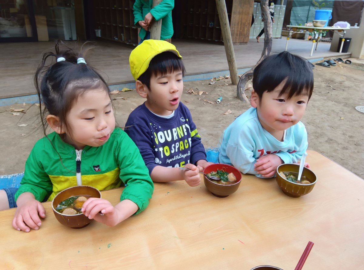 完成した味噌汁を園庭で食べる子どもたち