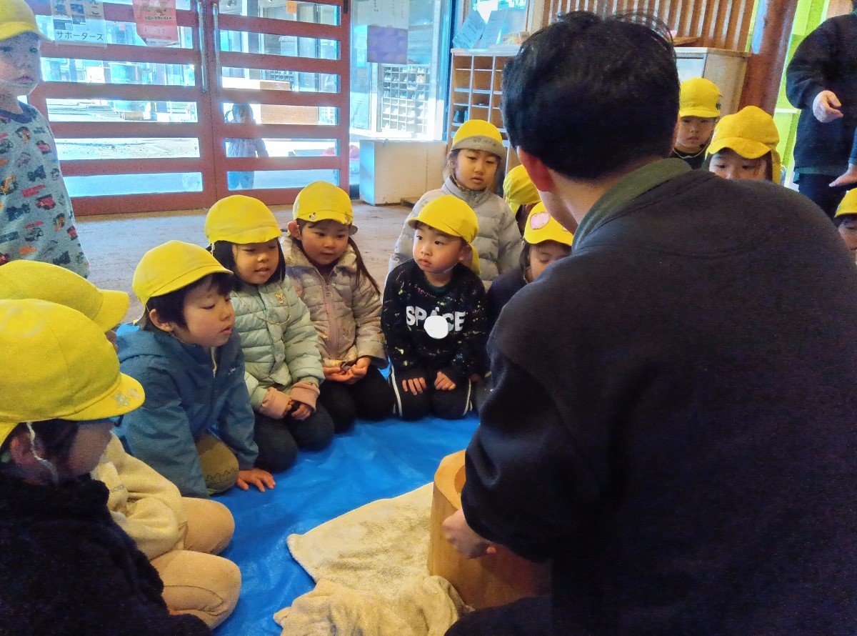 餅つき道具の説明を受ける子どもたち