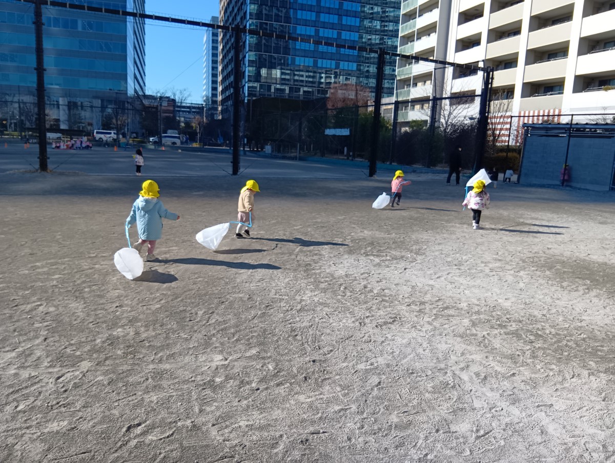 グラウンドで凧あげをする子どもたち