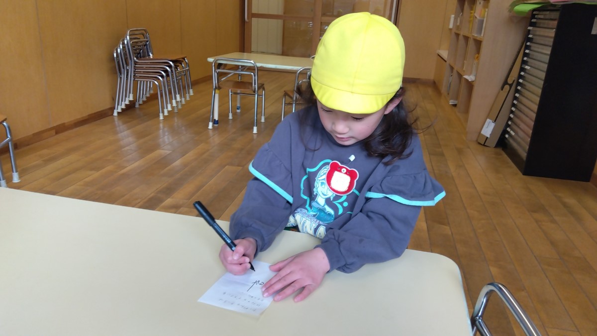 紙にペンでメモを書く子ども
