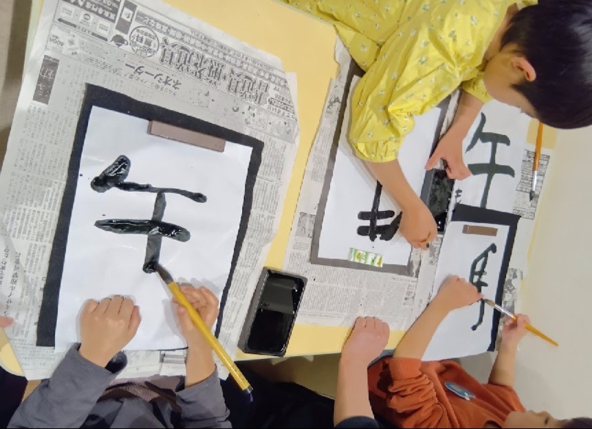筆と墨で文字を書く子どもたち