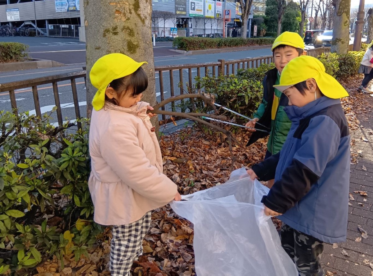 ビニール袋に落ち葉を集める子どもたち