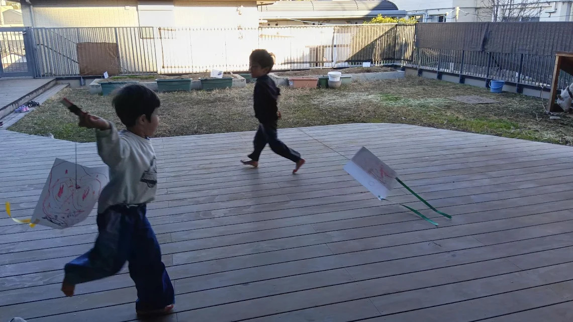 園のテラスで凧あげをする子どもたち