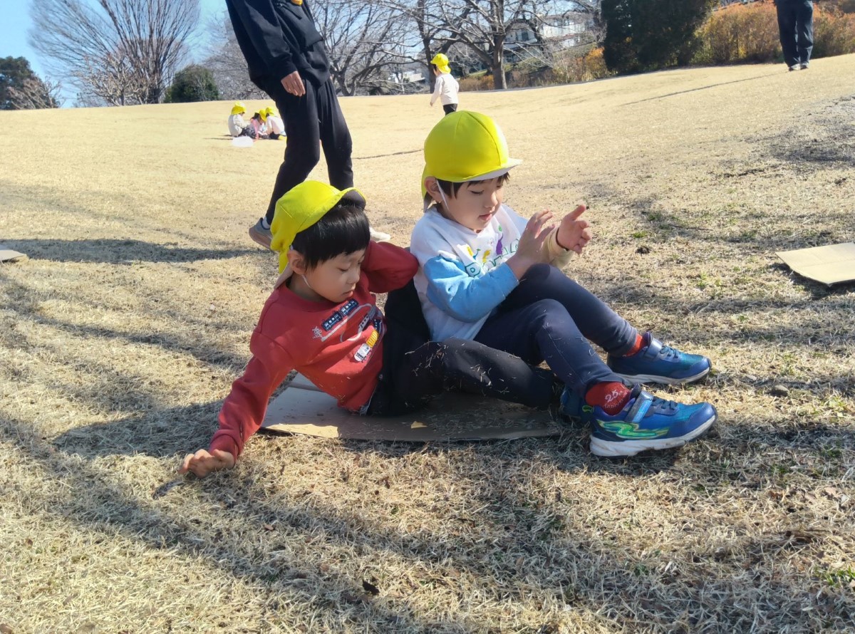 段ボールに二人で座って滑る子どもたち