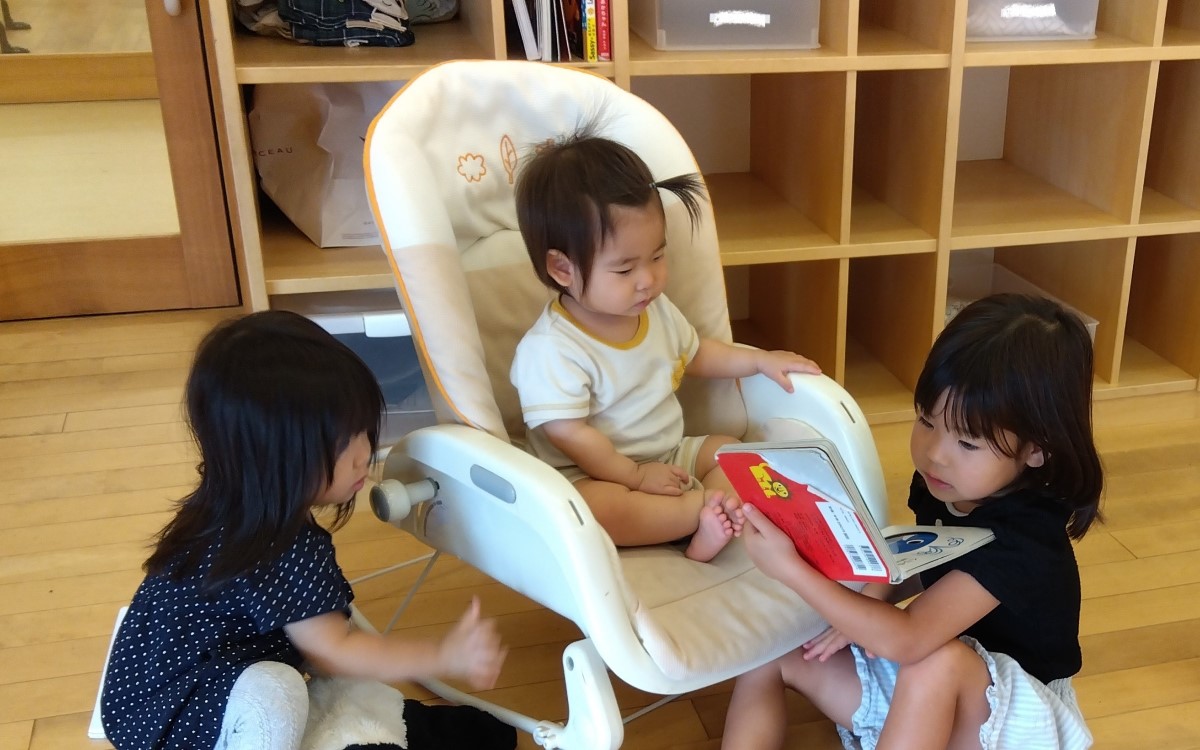 年下の子に絵本を読んであげる子どもの様子