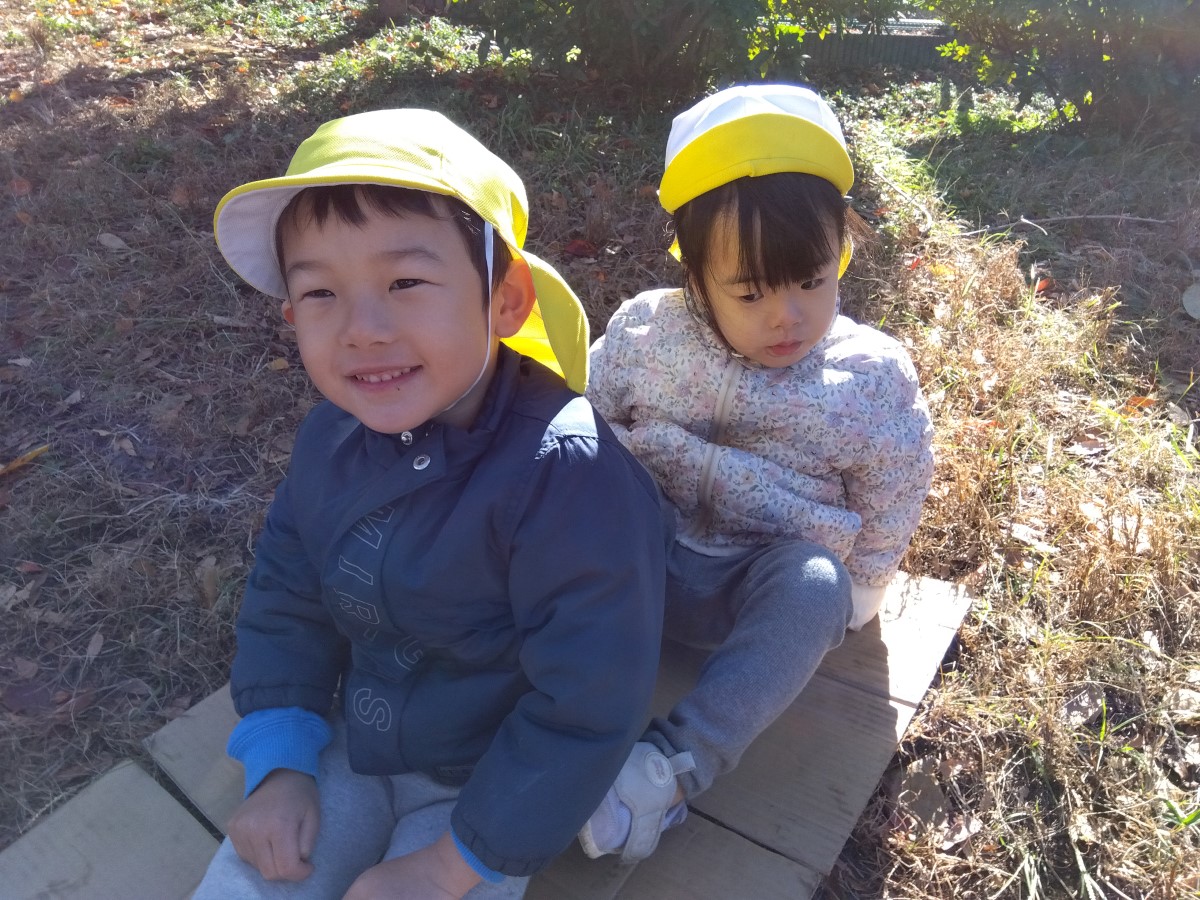 段ボールの上に2人で座る子どもたち