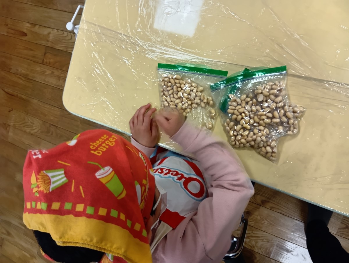 ポリ袋の上から大豆をグーで叩く子ども
