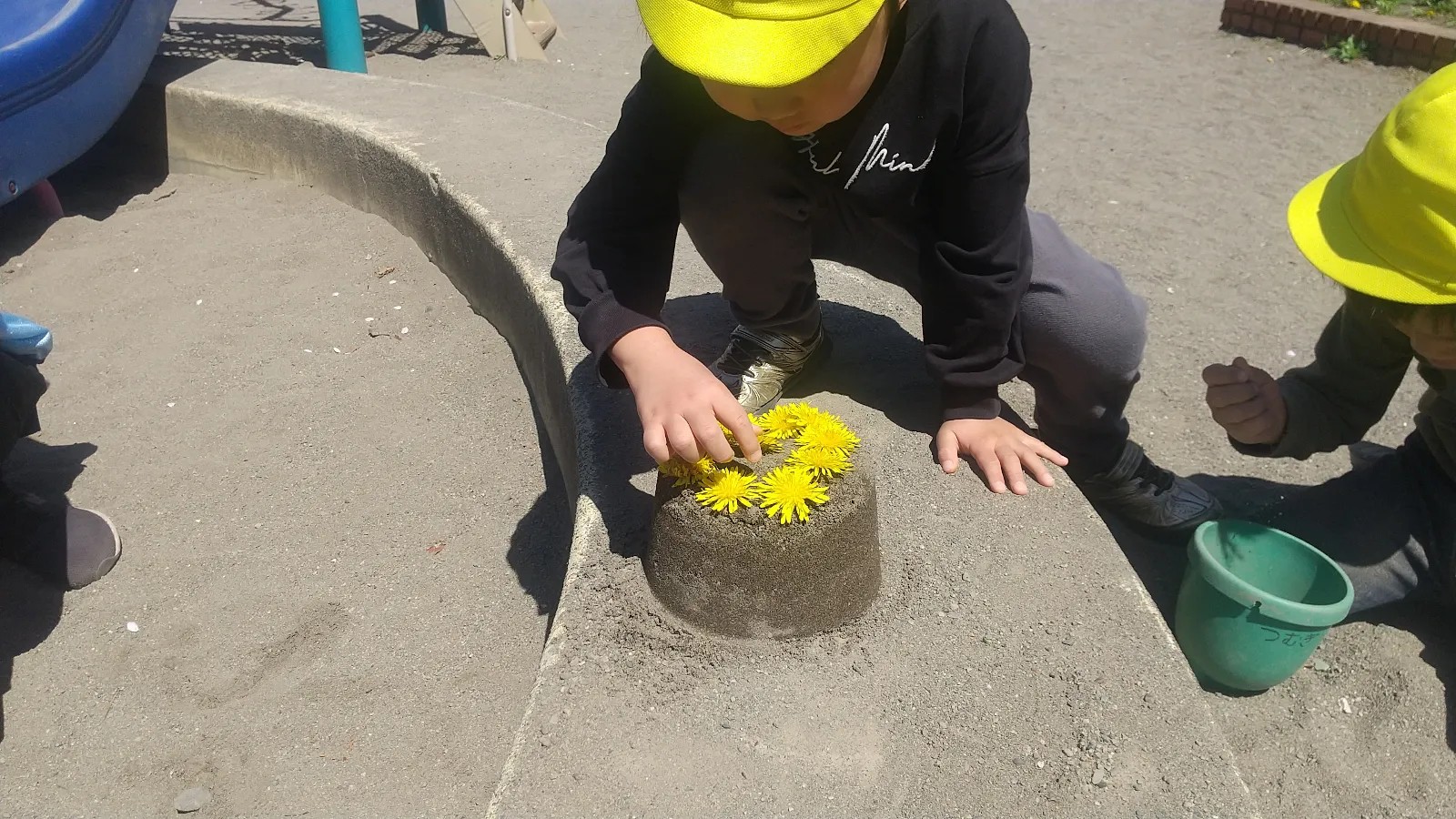 砂の上に花を並べる子ども