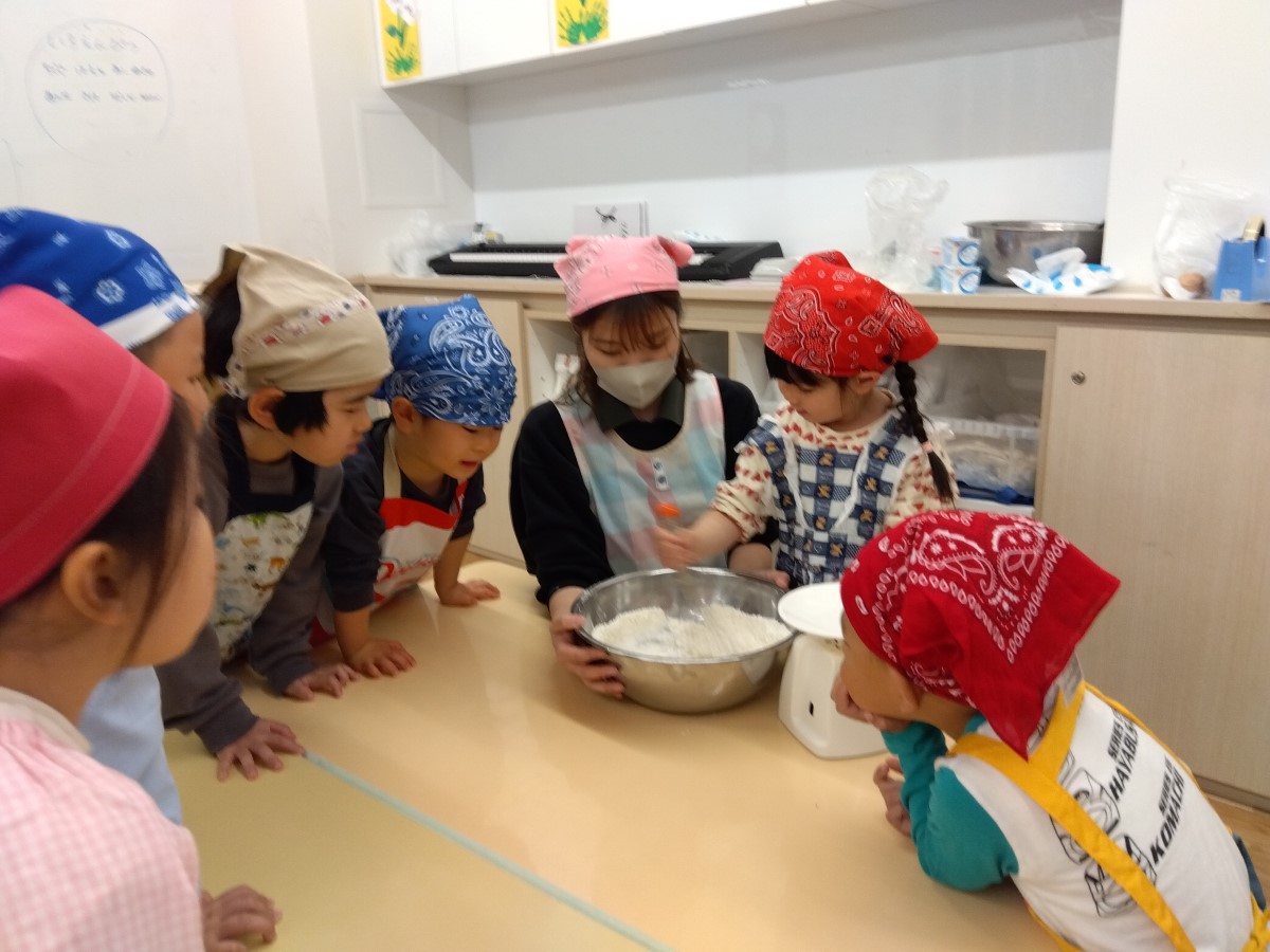 ボウルで粉を混ぜ合わせる子ども