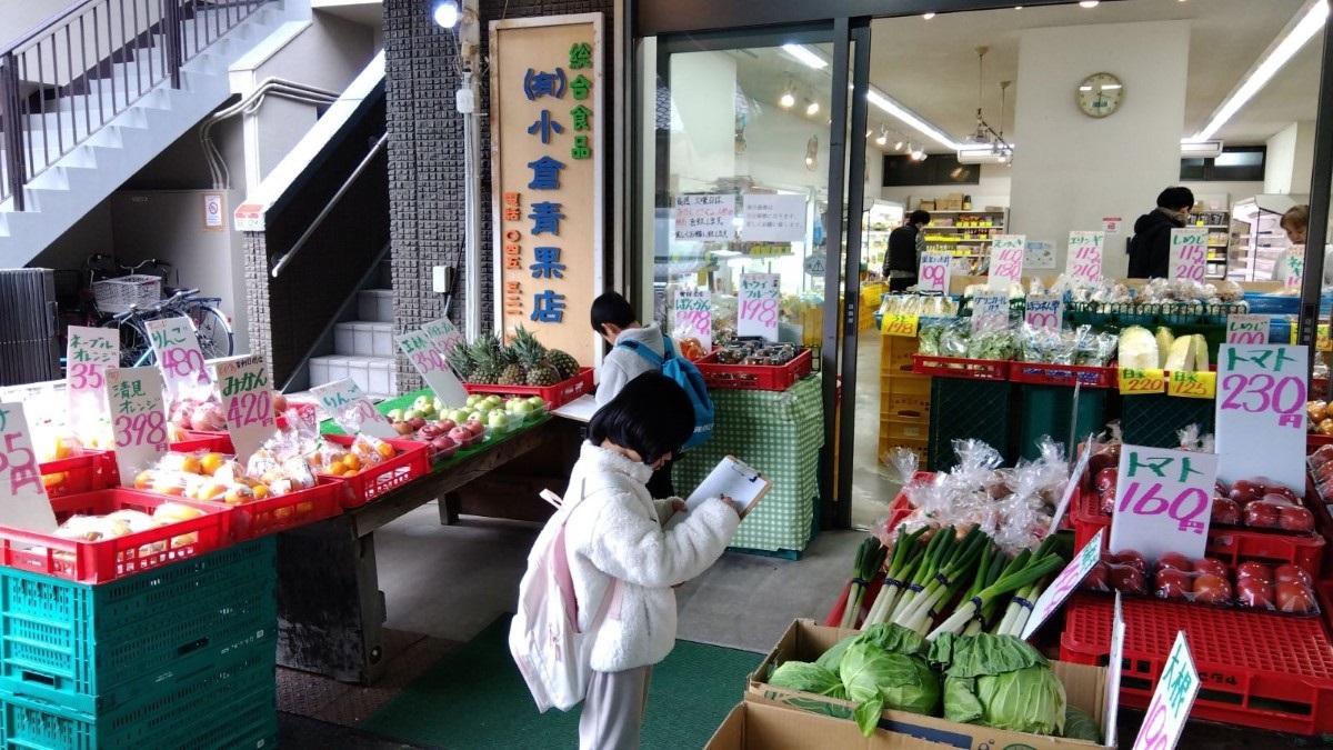 青果店でメモを取る子どもたち