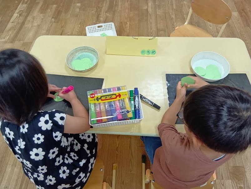 机では、二人の子どもが丸い画用紙に数字を書こうとしている