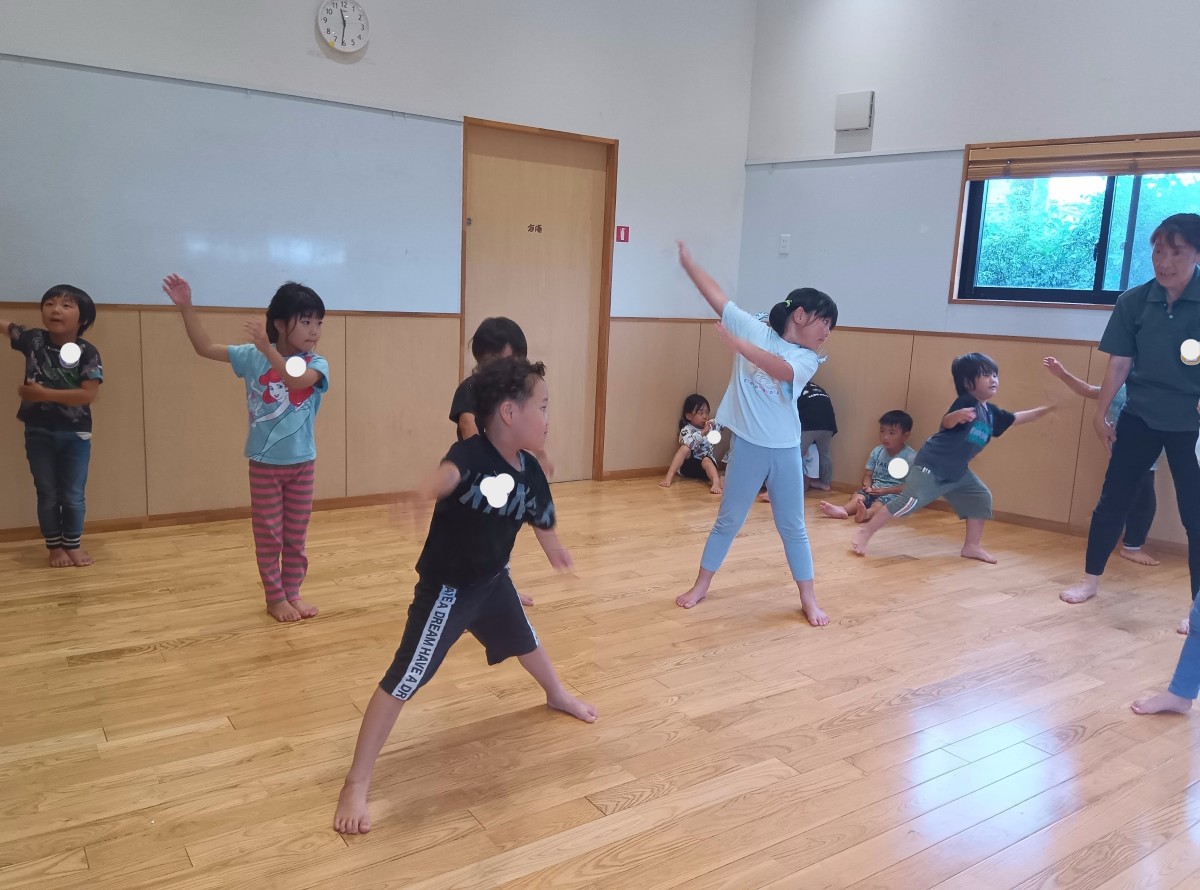 室内では、子どもたちが足や手を広げて体操をしている
