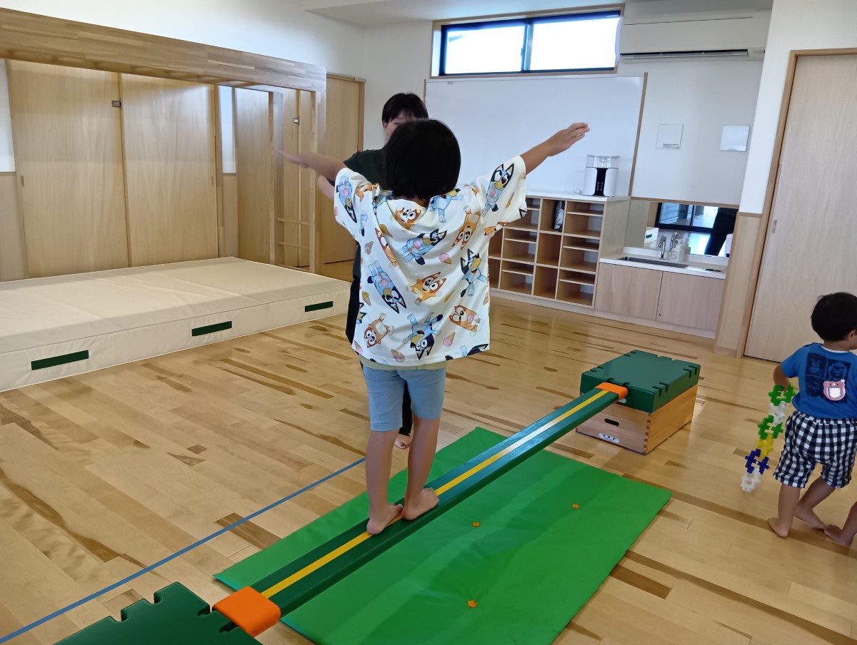一人の子どもが手を広げながら平均台の上を歩いている