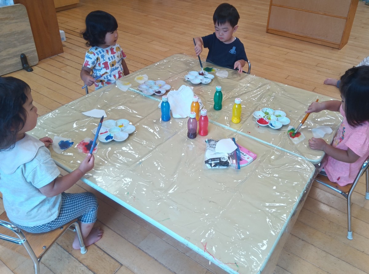 子どもたちは筆を使ってコーヒーフィルターに絵の具の色をにじませている