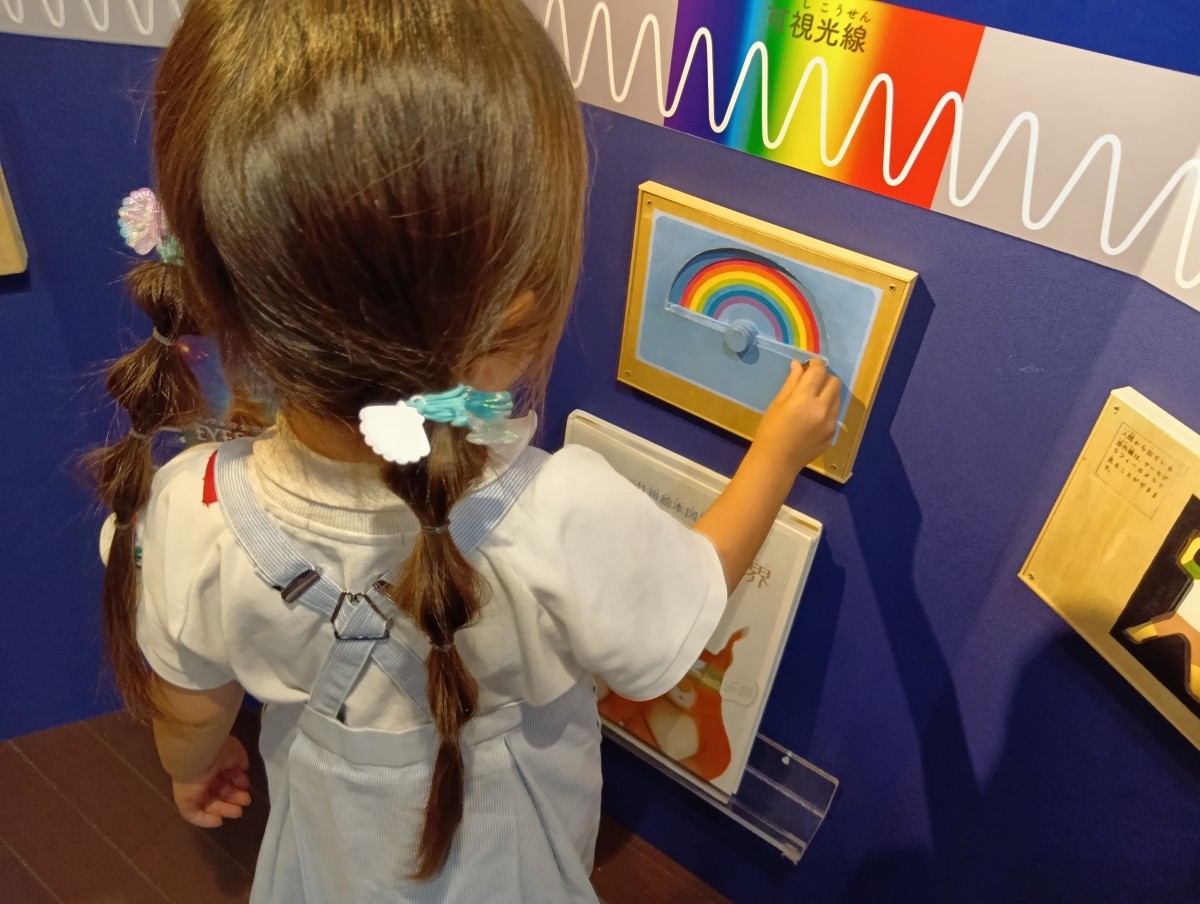 一人の子どもが壁の展示物に手を伸ばしている