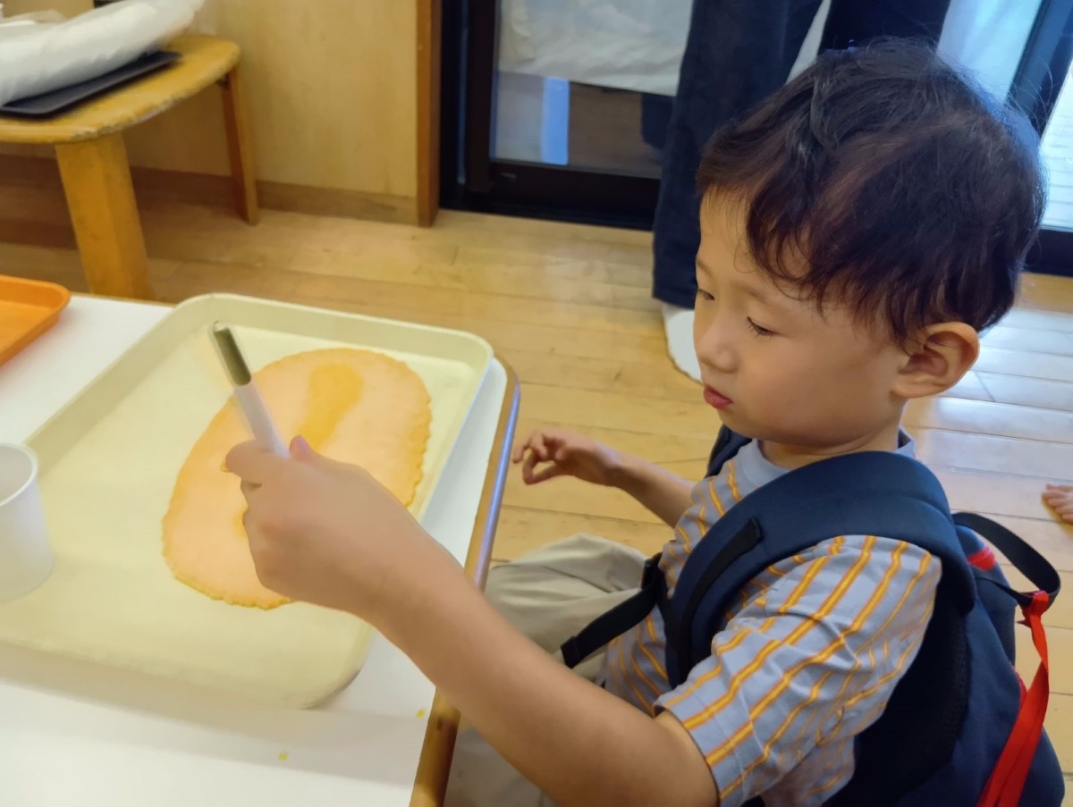 一人の子どもがせんべいにお絵かきをしようとしている