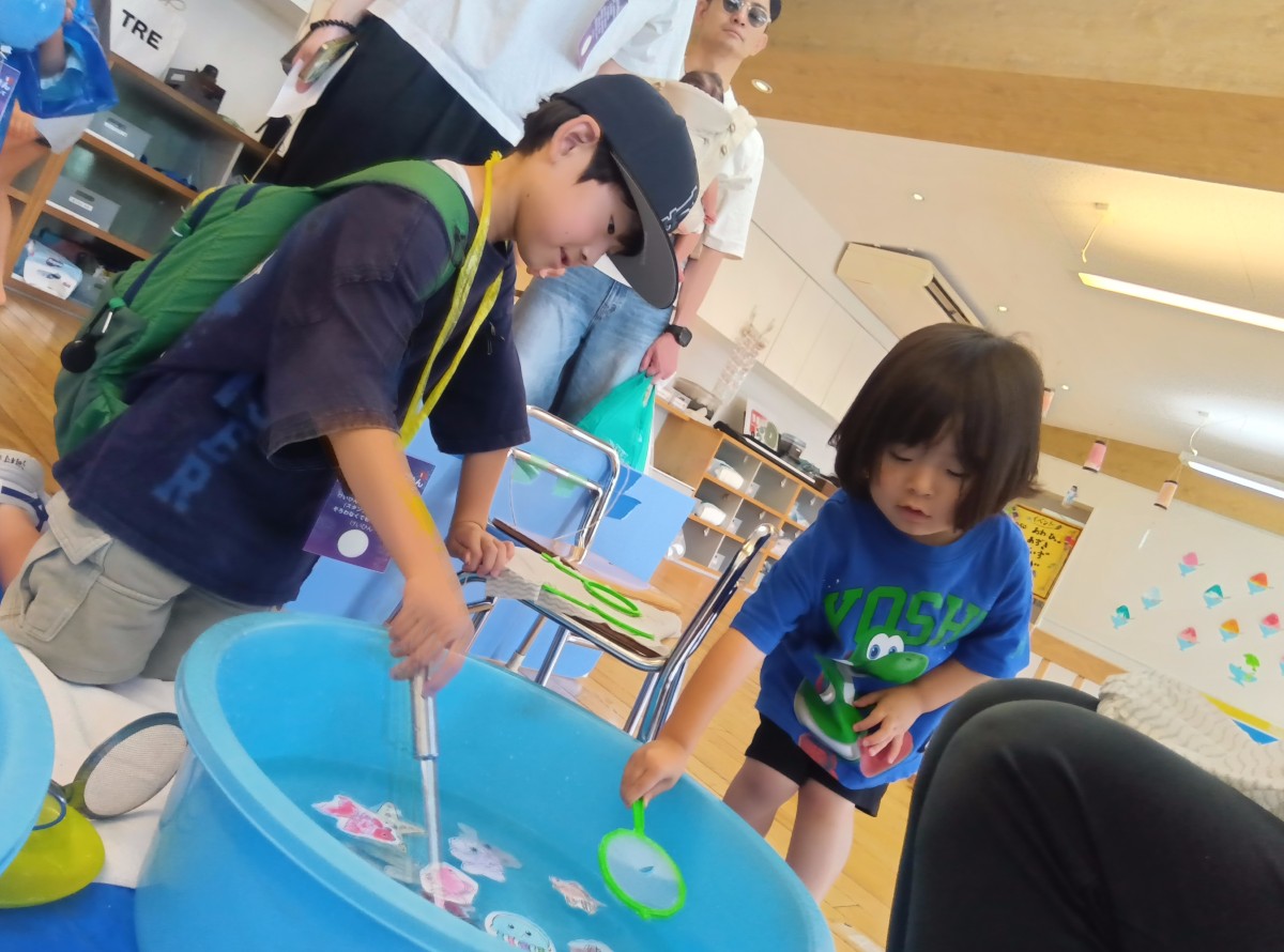 子どもたちは、お玉や網を使って魚釣りをしている