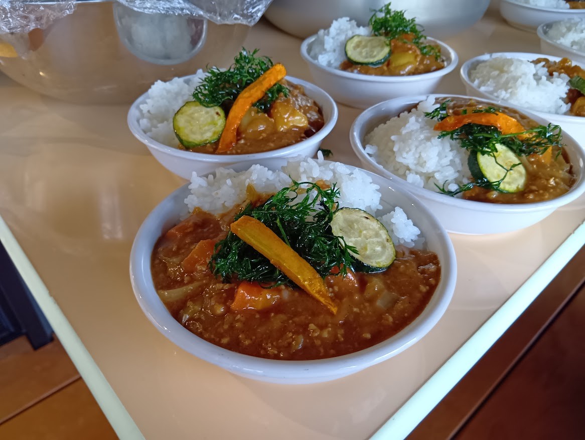 机の上には焼かれたズッキーニやニンジンが乗っているカレーライスが並んでいる