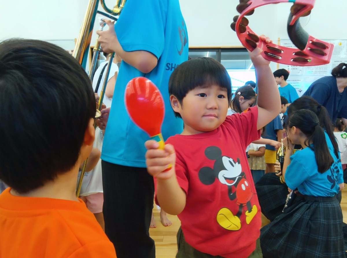 一人の子どもがタンバリンとマラカスを持ちあげて体を揺らしている