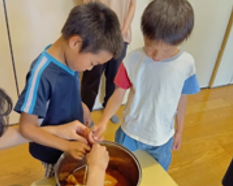 二人の子どもが玉ねぎの皮を煮込んだ液に布を浸している