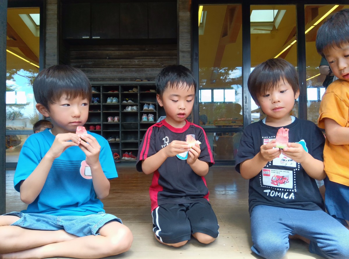 縁側で子どもたちがすいかを食べている