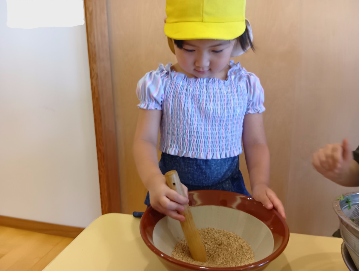 一人の子どもがすり鉢でゴマをすっている