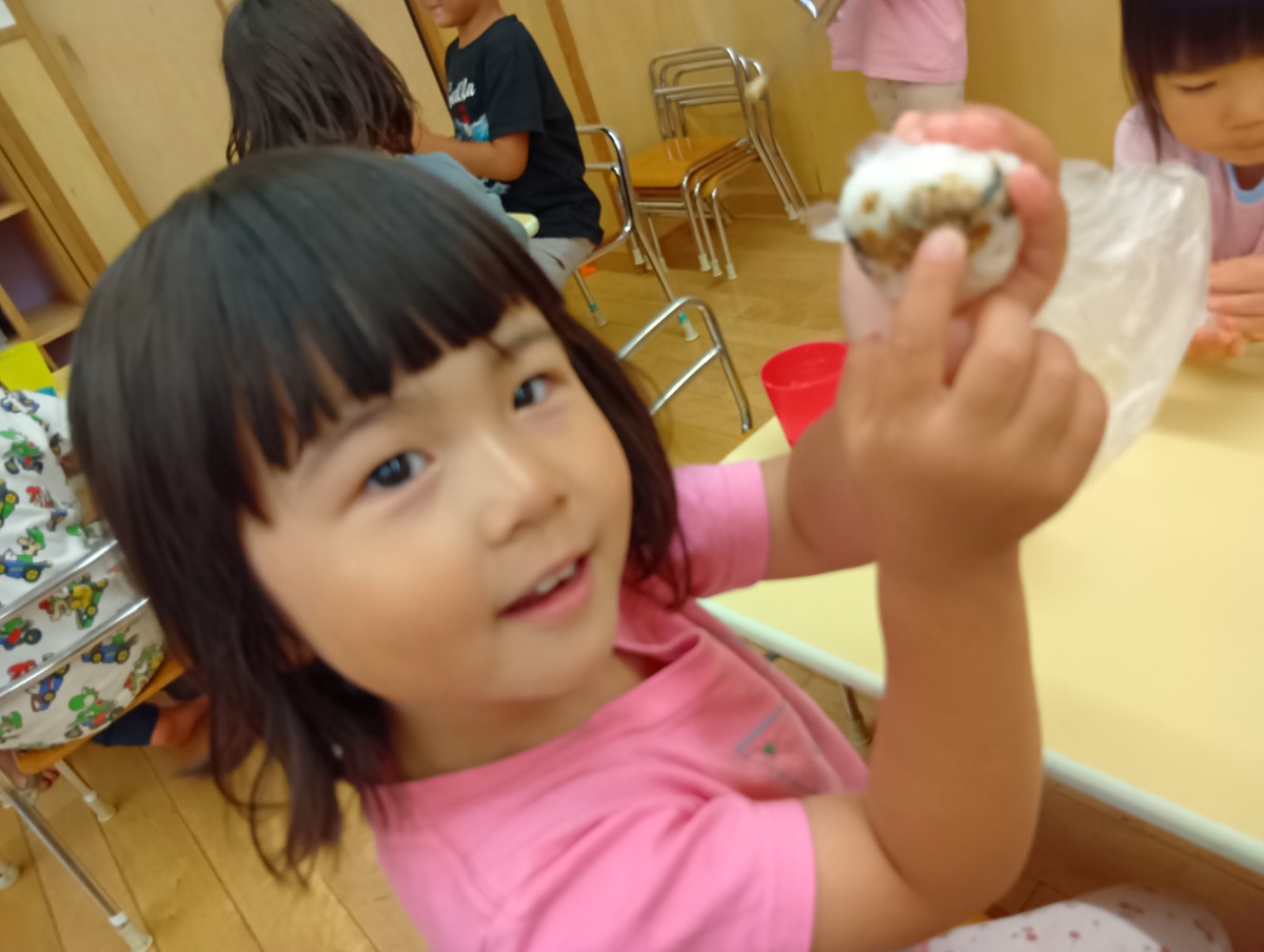 一人の子どもがビニール袋の中でまるまったふりかけご飯をこちらに見せている
