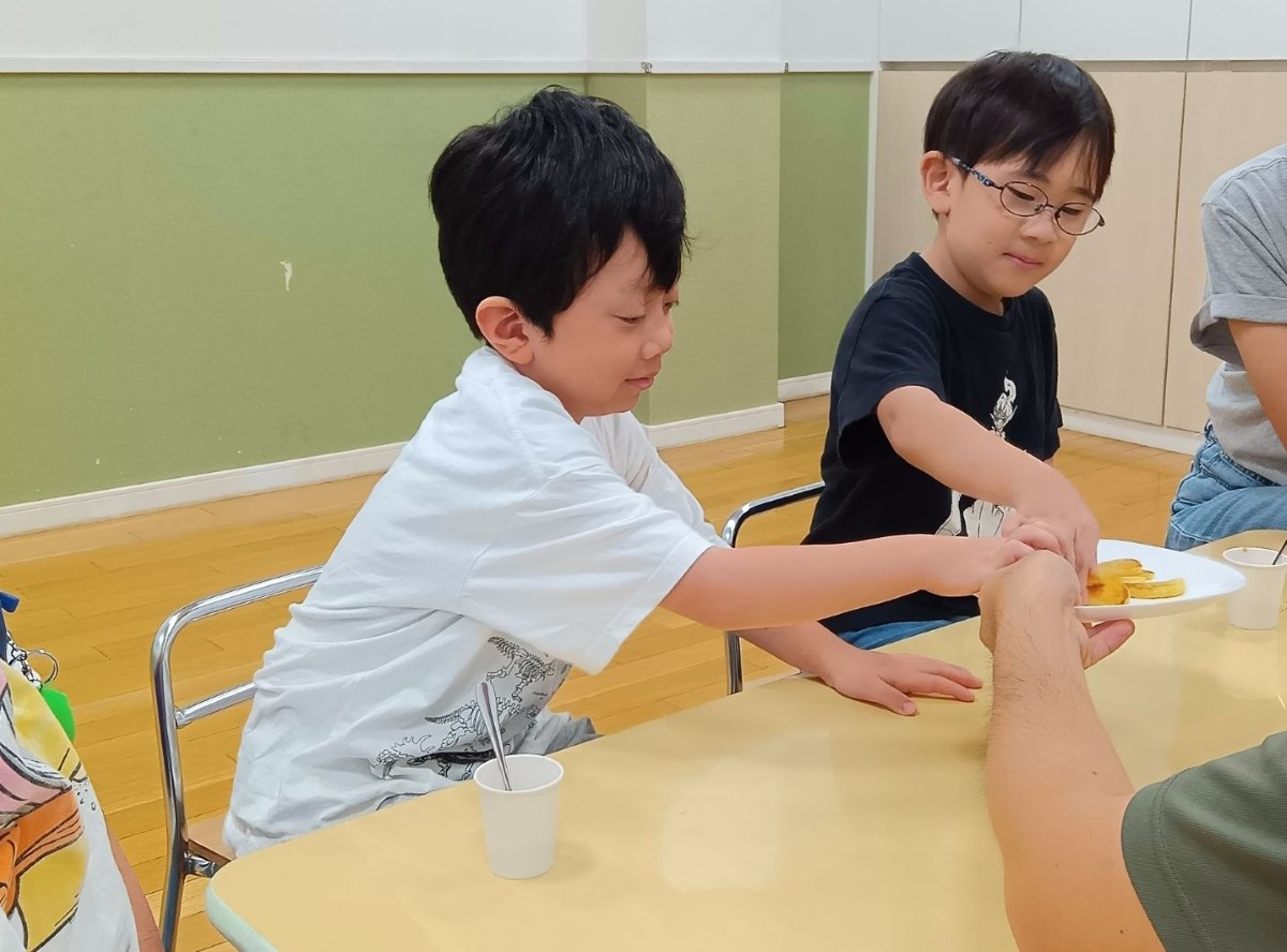 子どもたちが同じ皿の上のフライドポテトを一つずつ取っている